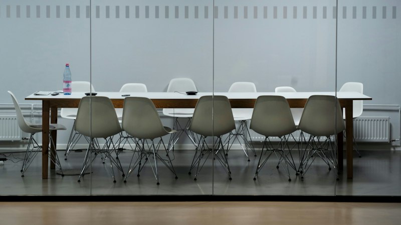 Empty meeting room with a long table and white chairs