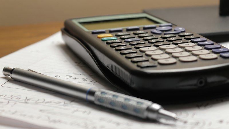 A calculator and pen resting on a sheet of paper
